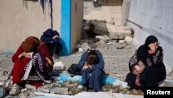 People rest next to damaged buildings as Palestinian arrive in Rafah after being evacuated from Nasser Hospital in Khan Younis due to the Israeli ground offensive against Hamas, in the southern Gaza Strip, Feb. 15, 2024.