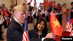 Tổng thống Mỹ Donald Trump cầm cờ Việt Nam khi được học sinh chào đón tại Văn phòng Chính phủ ở Hà Nội, Việt Nam, ngày 27/2/2019.