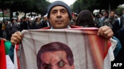 A protestor holds a burn picture of former Tunisian President Zine El Abidine Ben Ali during a demonstration in Tunis, Tuesday, Jan. 25. 2011. Hundreds of Tunisian protesters are demonstrating outside the prime minister's office to demand the removal of 