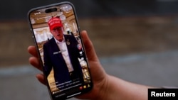 A woman poses with her smartphone displaying the @realdonaldtrump TikTok page, in Washington